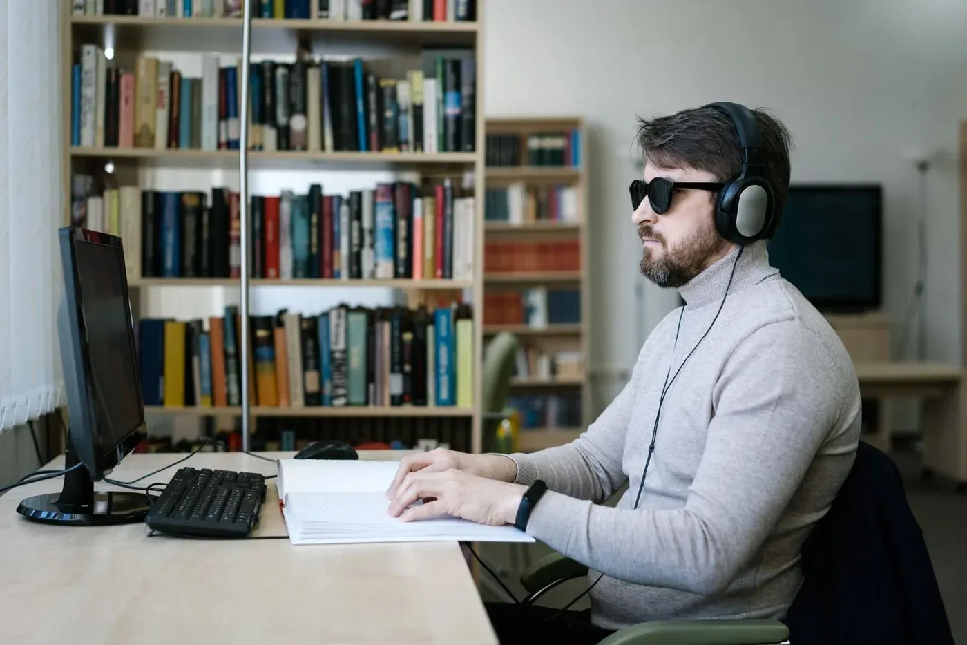 Un utilisateur non voyant lit en braille et travaille sur ordinateur : l’accessibilité numérique est une obligation pour de nombreux sites